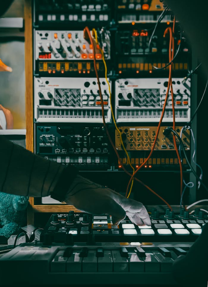 discover Musician using a synthesizer and controllers in a studio with electronic equipment.
